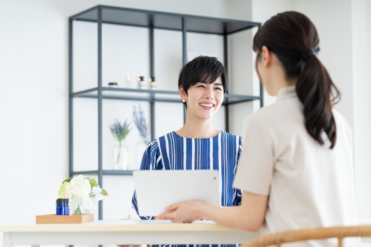 美容室で担当者が来店客にタブレットを見せて相談している様子（イメージ）
