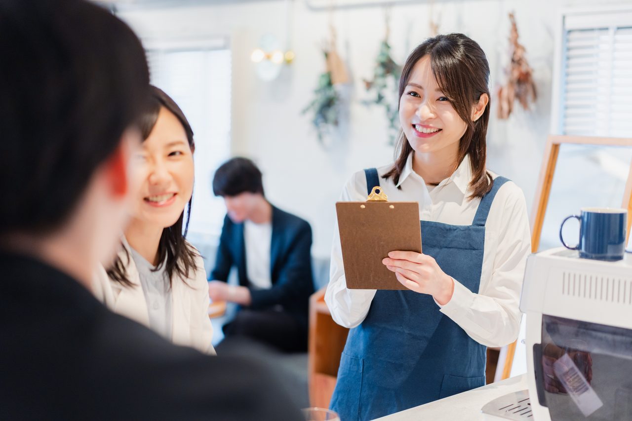 飲食店でスタッフがクリップボードを持って接客している様子（イメージ）