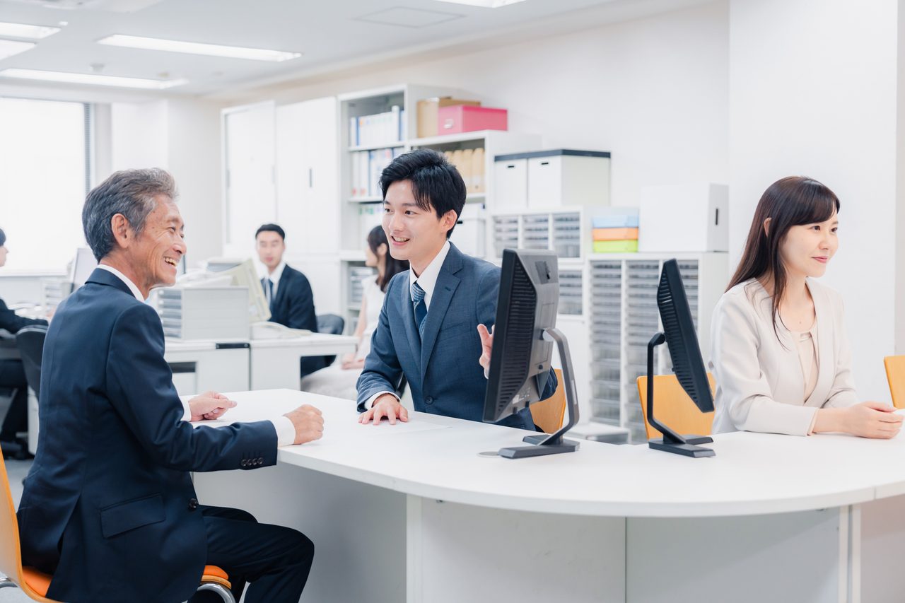 明るい窓口で職員と来訪者が向かい合って相談している様子（イメージ）